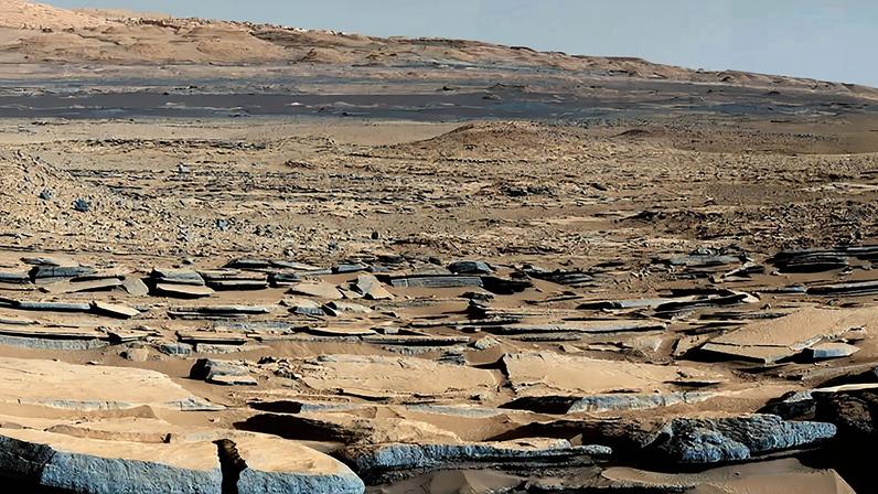 Uma parte da formação "Kimberley" em Marte capturada pelo rover Curiosity da Nasa. Os estratos em primeiro plano mergulham em direção à base do Monte Sharp, indicando fluxo de água em direção a uma bacia que existia antes da formação da maior parte da montanha.