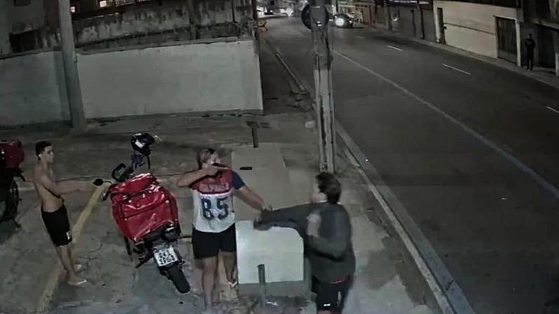 Imagem de câmera de segurança mostra o momento em que a moradora discute com entregadores na entrada de um condomínio na zona norte do Rio, na noite de terça-feira (14). Na imagem, ela aponta um objeto semelhante a uma arma; a mulher nega que estivesse armada.