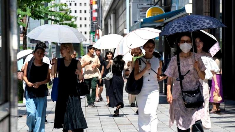 Pedestres usam sombrinhas para se proteger do sol escaldante em Tóquio; país sofre com cada vez mais ondas de calor