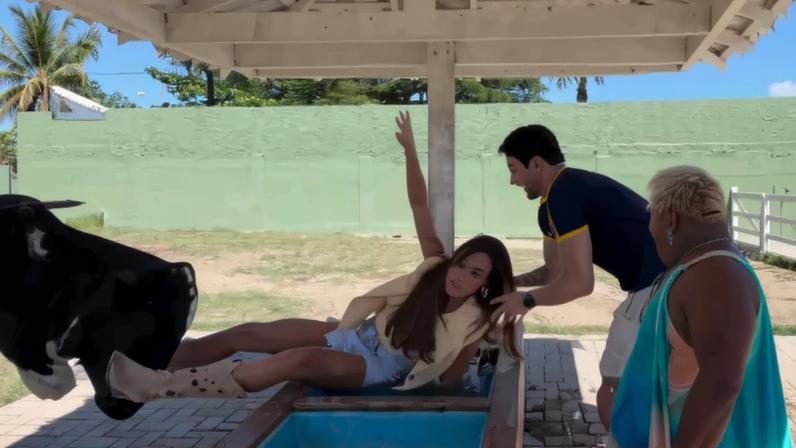 Sequência de três fotos mostra jovem caindo em tanque de areia sob cobertura. Outras três pessoas, incluindo uma mulher mais velha, observam a cena em área externa com parede verde ao fundo.