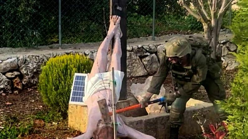 Um soldado israelense danifica a cabeça de uma estátua de Jesus crucificado em Debel, vila no sul do Libano