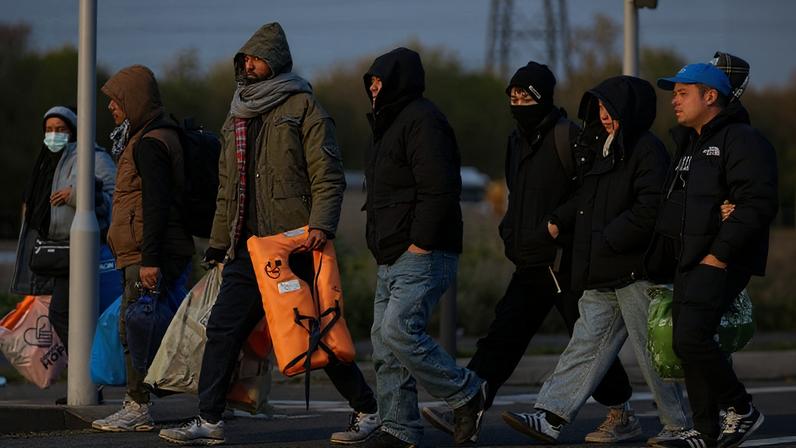 Migrantes caminham até a uma praia para serem levados para a Grã-Bretanha por meio do Canal da Mancha, em Grande-Synthe, perto de Dunquerque, norte da França