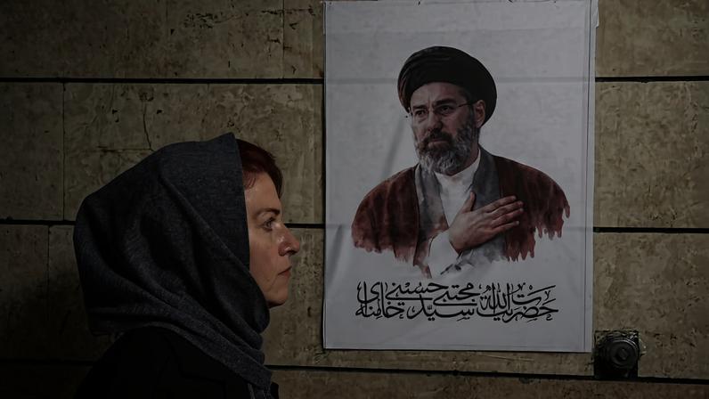 Uma mulher caminha em frente a um retrato de Mojtaba Khamenei em Teerã