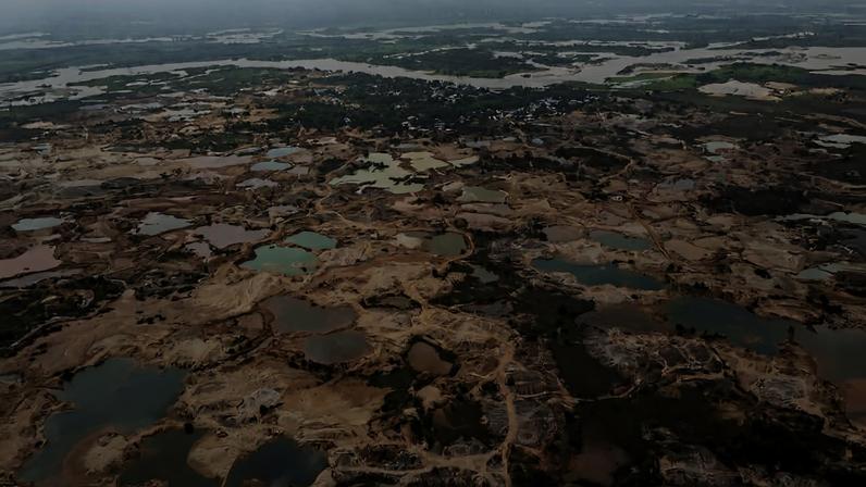 Vista aérea mostra grande extensão de solo degradado com múltiplas lagoas de diferentes tamanhos espalhadas. Vegetação escassa e áreas alagadas ao fundo indicam possível impacto ambiental.