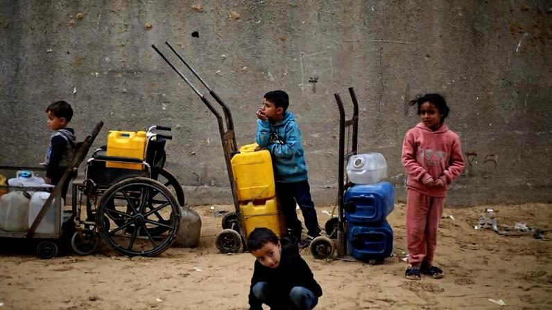 Crianças palestinas aguardam em fila de distribuição de água no campo de deslocados de Nuseirat, na região central da Faixa de Gaza