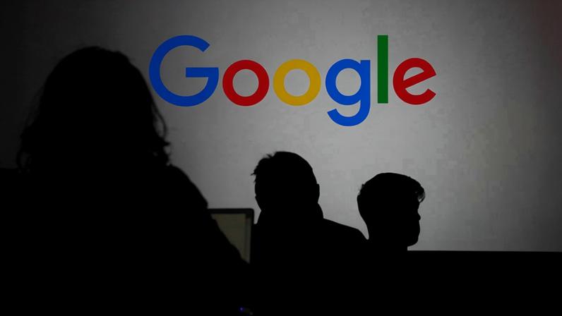 Silhueta de pessoas à frente do logo do Google durante evento da empresa em Paris