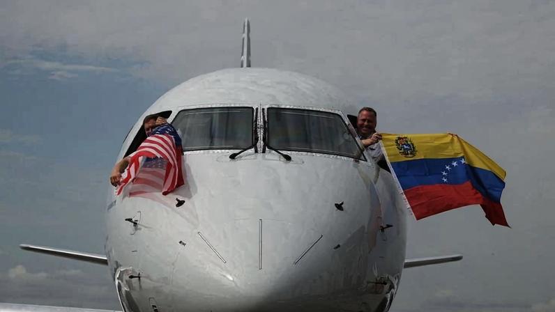 Pilotos do voo da American Airlines seguram bandeiras dos EUA e da Venezuela antes de decolar do aeroporto de Miami, na Flórida, com destino a Caracas