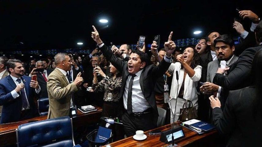 Senadores celebrando com os braços levantados no plenário