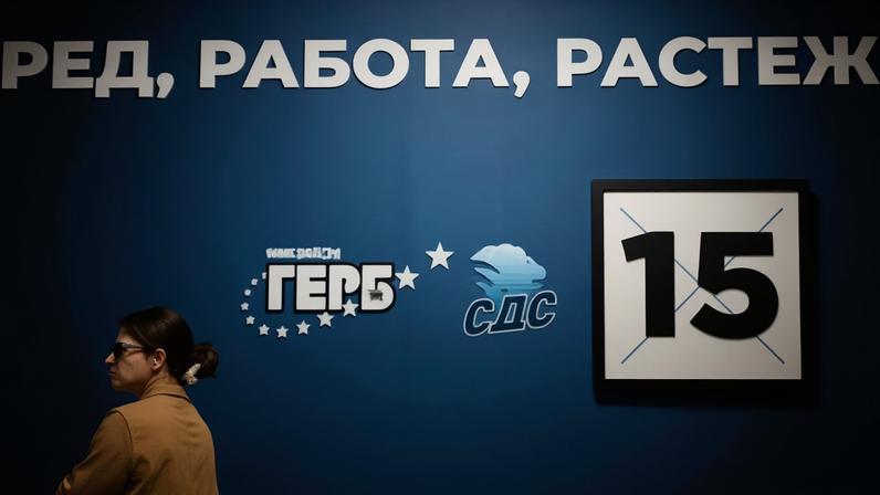 Uma mulher passa por um cartaz eleitoral do partido de centro-direita GERB em Sófia, Bulgária, em 14 de abril de 2026.