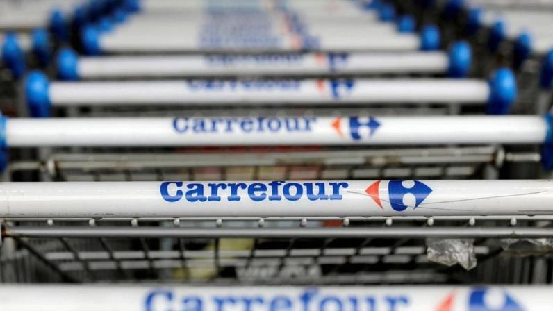 Cabos de carrinhos de compras Carrefour com nome e logo, alinhados em fileira.