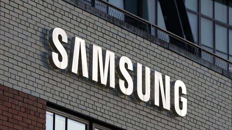 Logotipo da Samsung escrito com letras brancas, em um muro cinza escuro