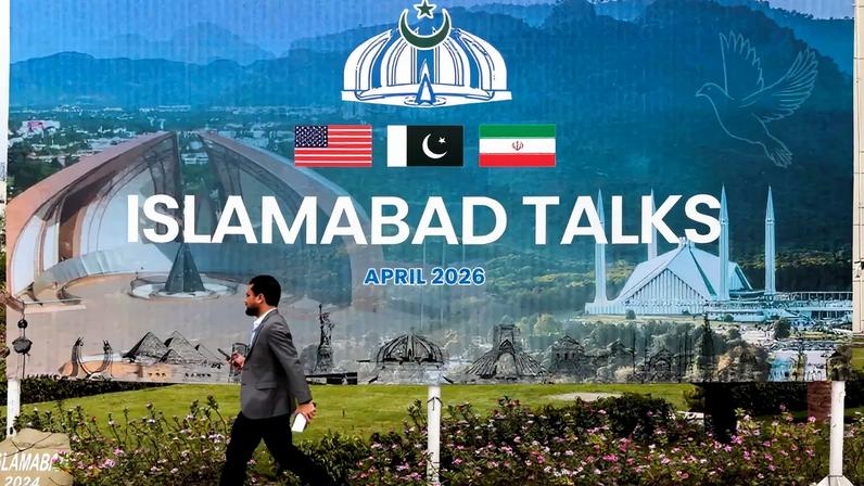 Um homem caminha diante de um outdoor perto do centro de mídia enquanto delegações dos Estados Unidos e do Irã são esperadas para realizar conversas de paz em Islamabad, Paquistão, em 11 de abril de 2026. REUTERS/Asim Hafeez