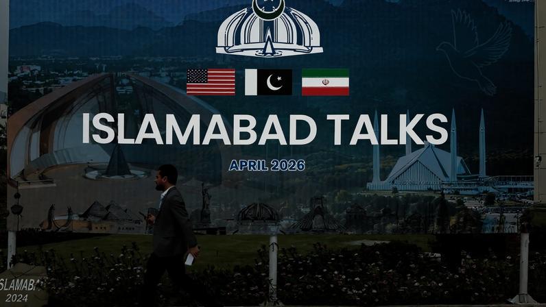 Um homem caminha diante de um outdoor perto do centro de mídia enquanto delegações dos Estados Unidos e do Irã são esperadas para realizar conversas de paz em Islamabad, Paquistão, em 11 de abril de 2026. REUTERS/Asim Hafeez