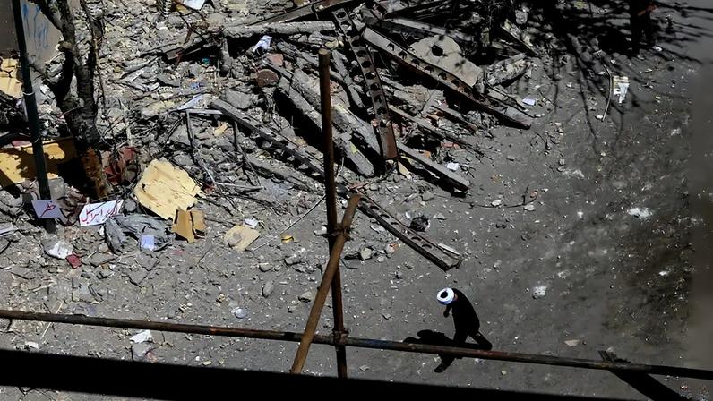 14 de abril de 2026 - Um homem caminha ao lado dos destroços de um prédio residencial em Teerã atingido por ataques no dia 4 de março. Foto: REUTERS/Thaier Al Sudani