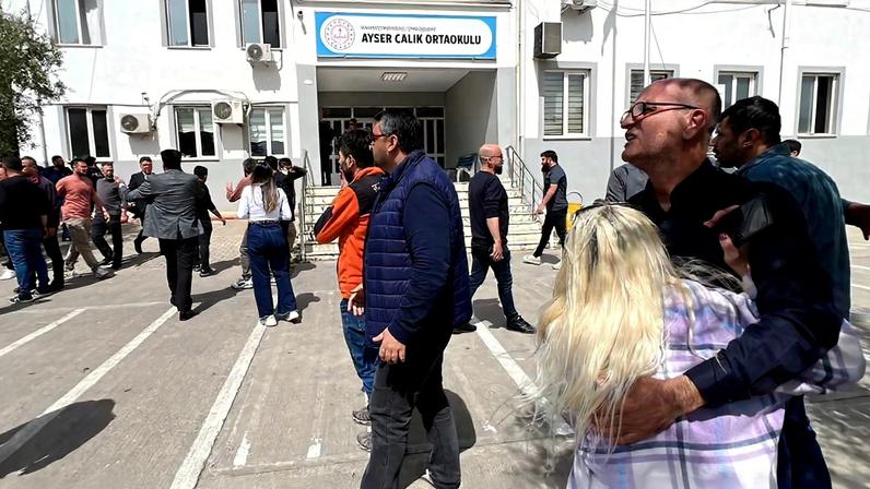 Pessoas esperam em frente ao prédio da escola após ataque no sudeste da Turquia 15 de abril de 2026 IHA (Ihlas News Agency) via REUTERS