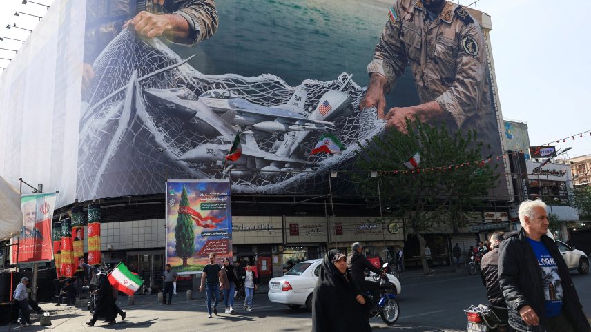 Pessoas caminham perto de uma propaganda anti-EUA em um prédio em Teerã — Foto: REUTERS/Thaier Al-Sudani