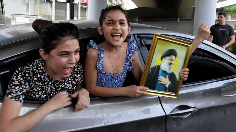 Menina segura foto do líder assassinado do Hezbollah, Hassan Nasrallah, enquanto volta para casa nos subúrbios de Beirute