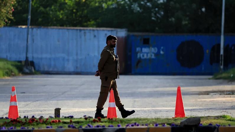 Um policial protege uma estrada bloqueada com contêineres de transporte, por medidas de segurança perto da casa do presidente, enquanto o Paquistão se prepara para receber os Estados Unidos e o Irã para uma segunda rodada de negociações de paz em Islamabad