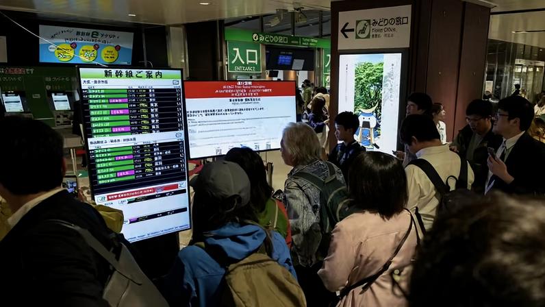 assageiros observam telas eletrônicas que anunciam a suspensão do serviço do trem-bala Tohoku Shinkansen devido a um terremoto, em Sendai, no Japão
