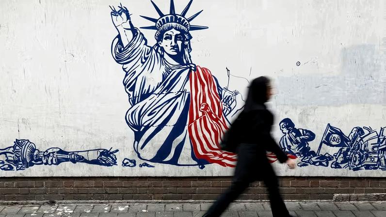 Mulher passa por mural anti-EUA em Teerã, capital do Irã
