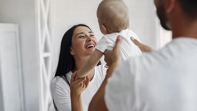 Pai e mãe brincando com o bebê — Foto: Freepik