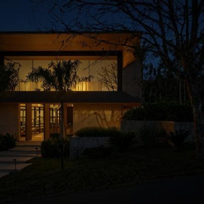 Casa em declive tem átrio com árvore e 9 suítes com vista para o verde