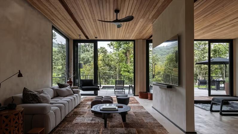 SALA DE ESTAR | Deste ângulo, destaca-se a permeabilidade da casa com o exterior. Sofá da Ilustre Móveis, que também forneceu o pufão ao centro, composto com mesa redonda da Moldd.br e par de bancos da Artefacto. Almofadas da Quacker