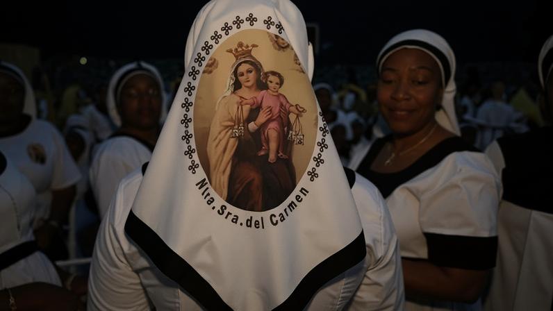 Catholics gather for a mass led by Pope Leo XIV, one wearing a headscarf with the back showing a picture of Mary and Jesus