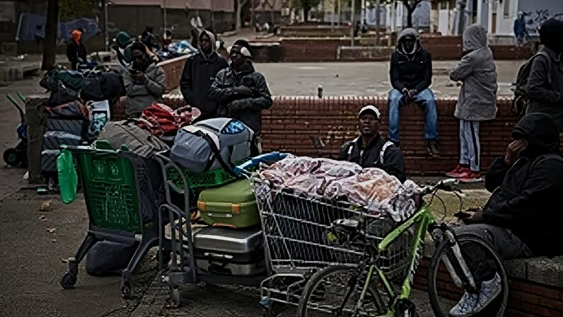 Migrants sit together with their belongings after being evicted by police from an abandoned school where they had been living in Badalona, 17 December, 2025