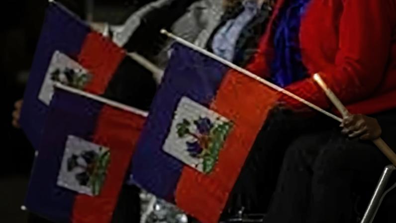 People holding blue and red Haitian flags and candles.