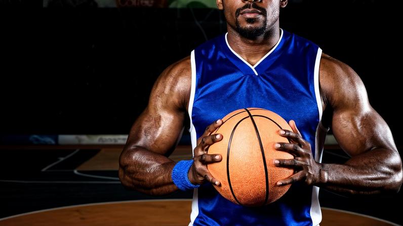 Jogador segura bola de basquete na quadra