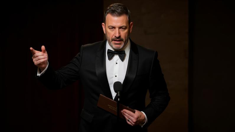 Jimmy Kimmel in tuxedo on stage with microphone