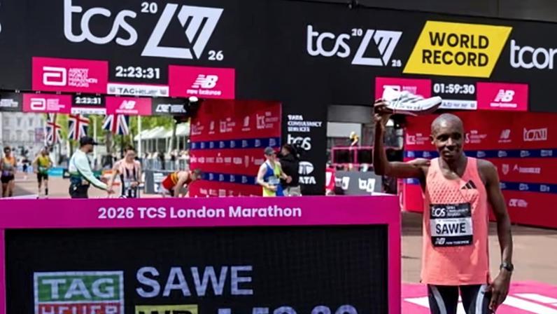 Sabastian Sawe celebrates beside the Tag Heuer race clock showing his official time of 01:59:30