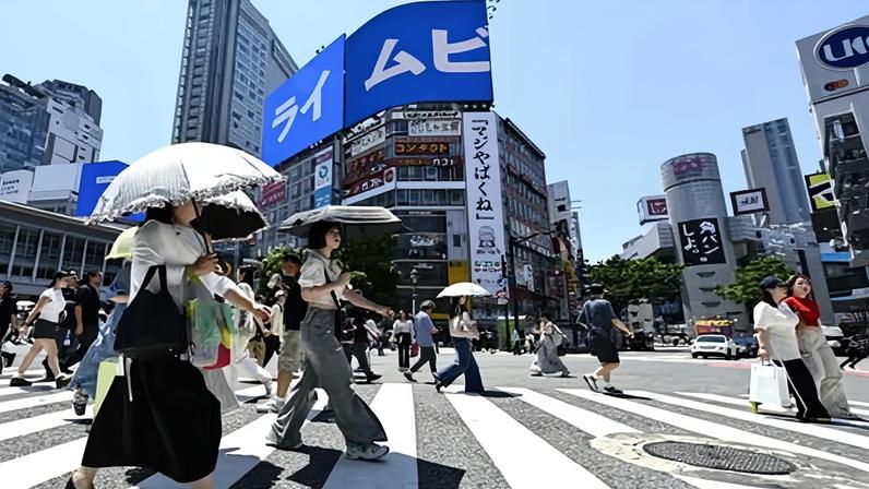 People with parasol's on pedestrian crossing in Tokyo, Japan, with tall buildings behind