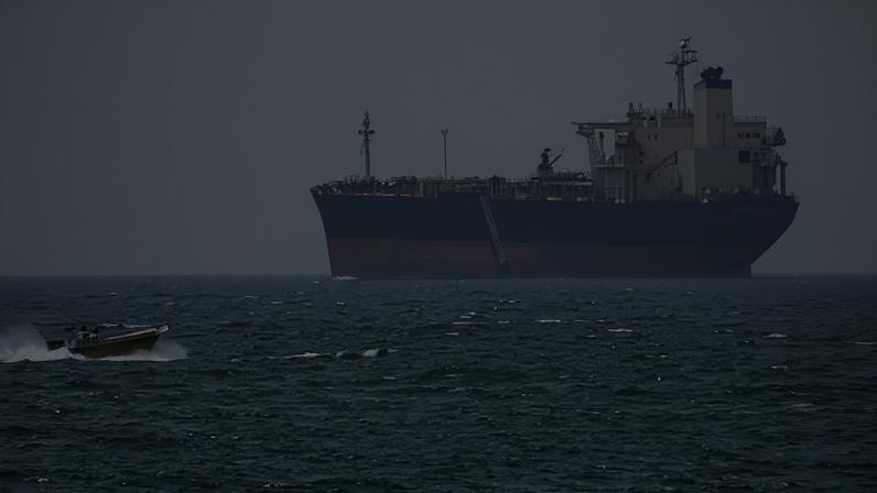 A boat sails past a tanker anchored on the Strait of Hormuz off the coast Qeshm island, Iran, on Saturday.