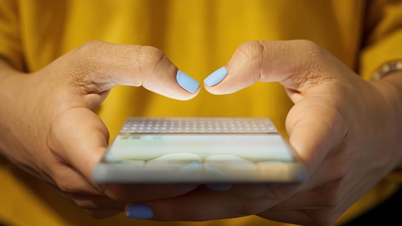 Close-up of hands typing on a smartphone