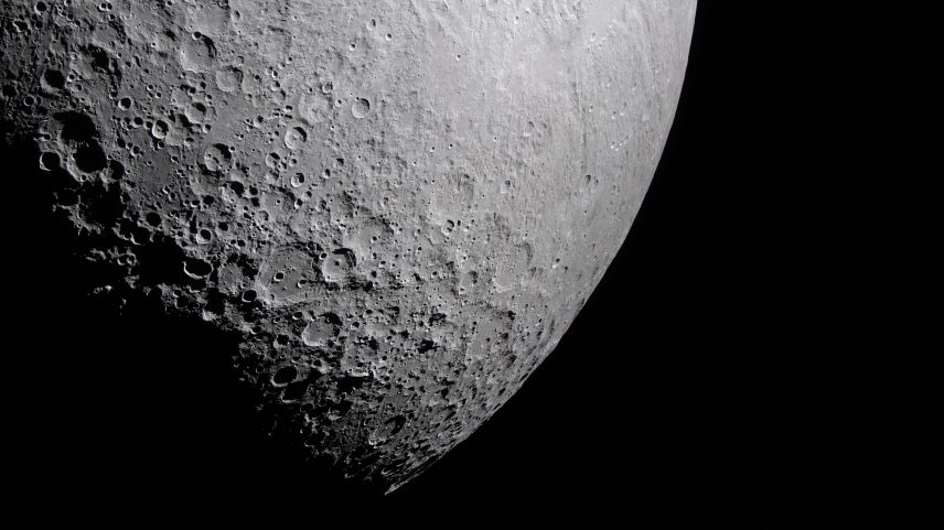 Part of the Moon stands out against the blackness of space. Its surface is marked with many craters of different sizes. The craters are mostly on the left and bottom. The upper right portion of the Moon's surface is much smoother.