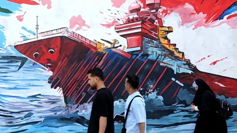 Pedestrians walk past a mural in Tehran, 22 April 2026.