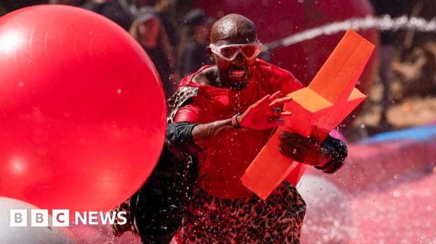 Sir Mo Farah splashes through red water carrying a large red star