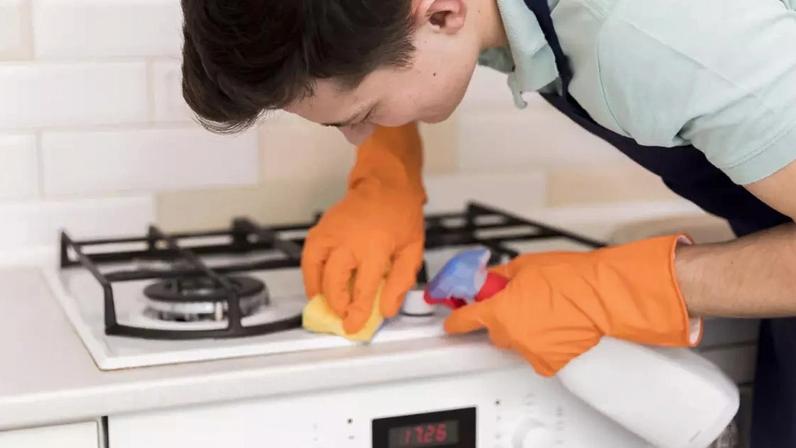 Homem na cozinha limpando o fogão
