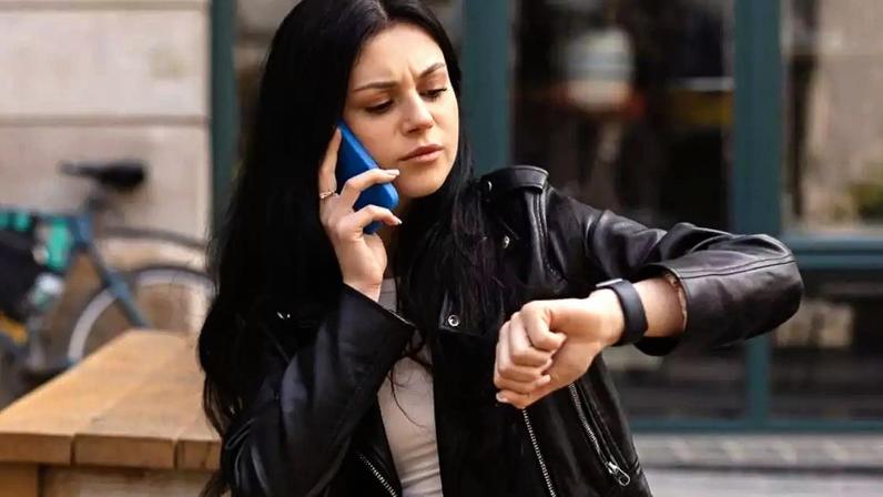 Mulher olhando o relógio e falando no celular