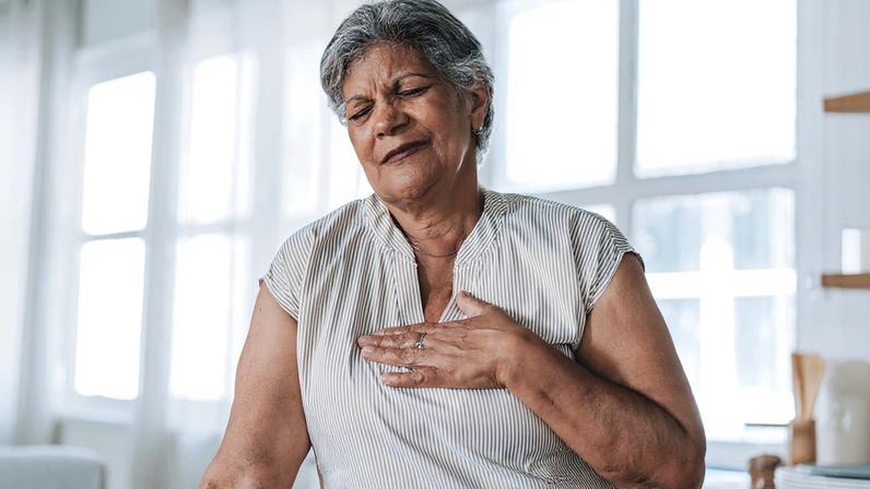 Foto colorida de mulher com a mão no peito - Cardiologistas explicam quais são os primeiros sintomas do infarto - Metrópoles - sedentarismo