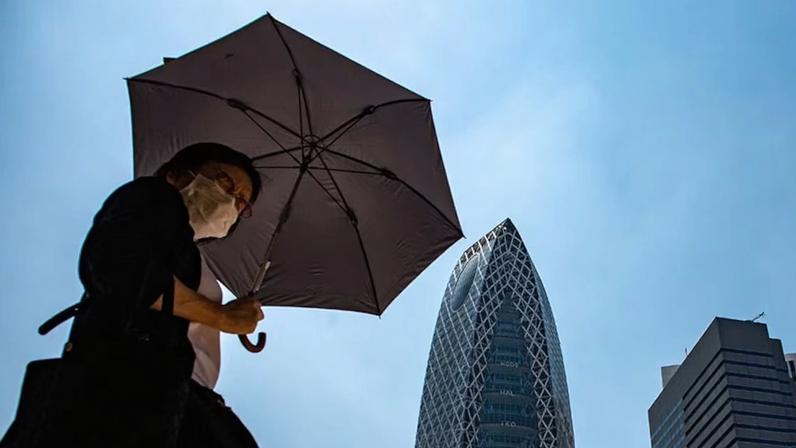 Mulher utiliza guarda-chuva para se proteger do sol, em meio a uma intensa onda de calor, em Tóquio, no Japão.
