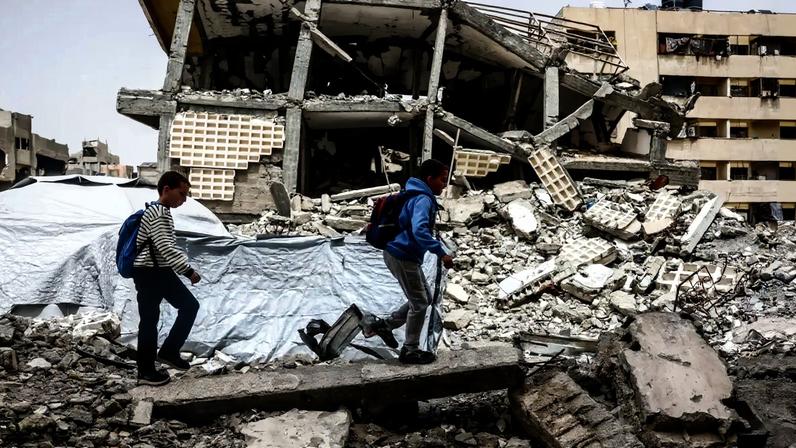 Meninos palestinos caminham em meio aos escombros de prédios destruídos em Khan Yunis, no sul da Faixa de Gaza, em 18 de abril de 2026.