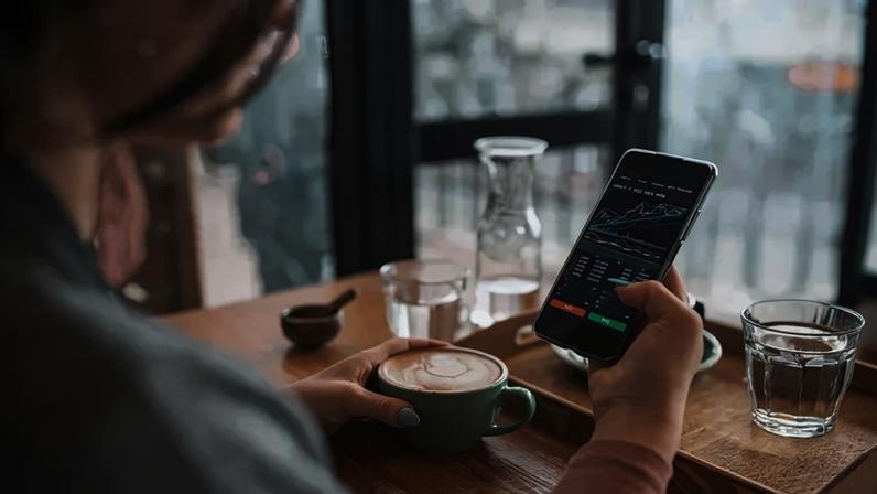 Unrecognisable woman using smartphone buy cryptocurrency at a coffee shop, blockchain investment, decentralize and Stock market concept. (ArtistGNDphotography/Getty Images)