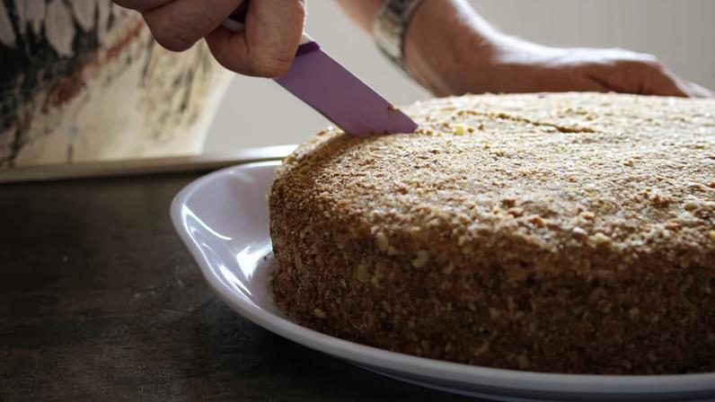 A mulher está cortando bolo de mel com uma faca. Foto: dalaxey - stock.adobe.com/Adobe st