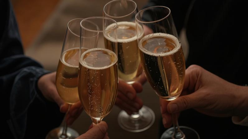 People clinking glasses with sparkling wine indoors , closeup