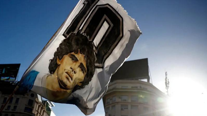Um torcedor agita uma bandeira com o rosto de Diego Maradona durante uma manifestação que pedia investigação e justiça pela morte da lenda do futebol (Marcos Brindicci/Getty Images)