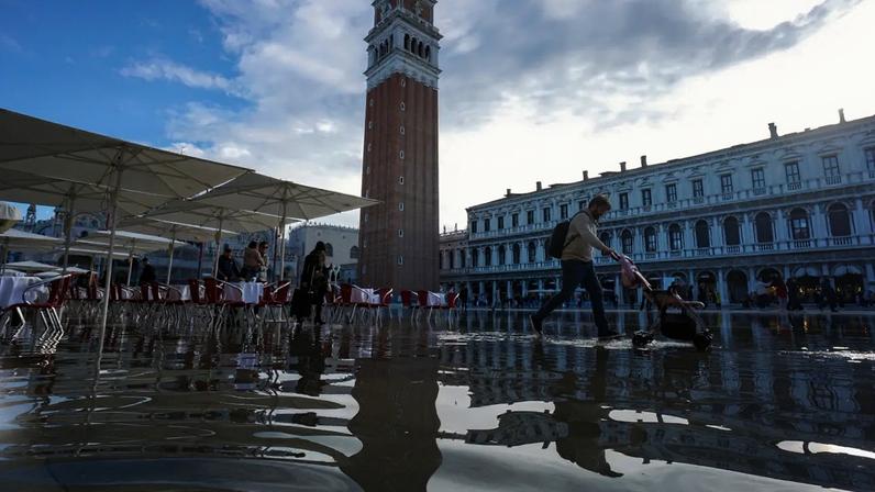 Turistas enfrentam inundação na Praça de São Marcos, em Veneza, Itália, no sábado, 26 de novembro de 2022. A frequência das enchentes, conhecidas como acqua alta, tem aumentado de forma constante