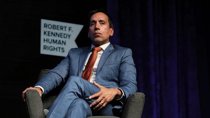 José E. Feliciano sits in a chair onstage during the 2021 Robert F. Kennedy Human Rights Ripple of Hope Award Gala in 2021.
